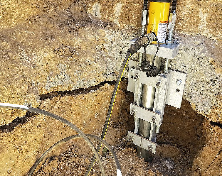 Close-up of an underground utility installation with cables and a clamp.