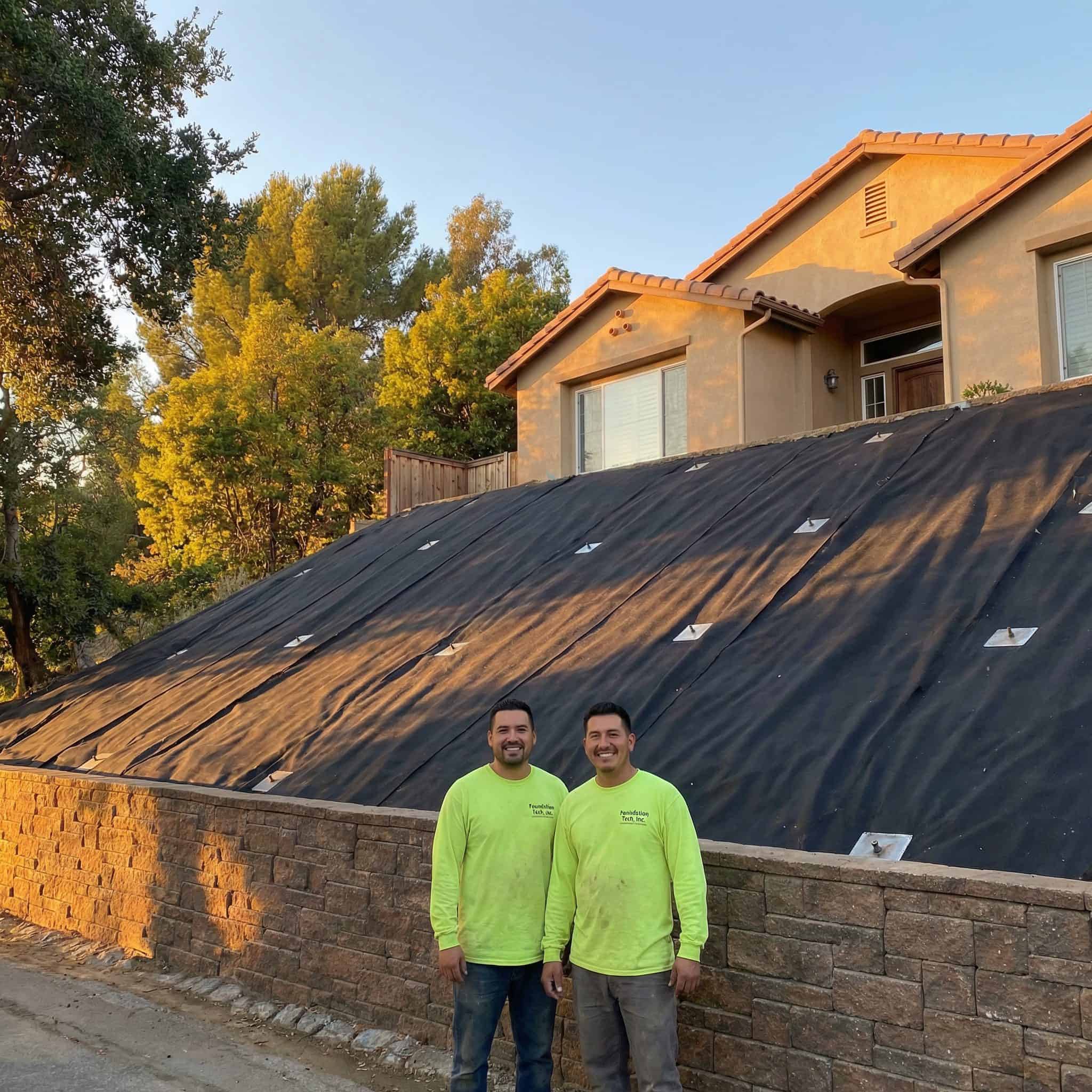 Avari Foundation Repair Services workers standing in front of a completed residential slope repair using geogrids and erosion control.